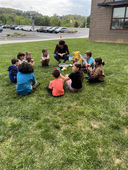 Students sitting in grass with teacher